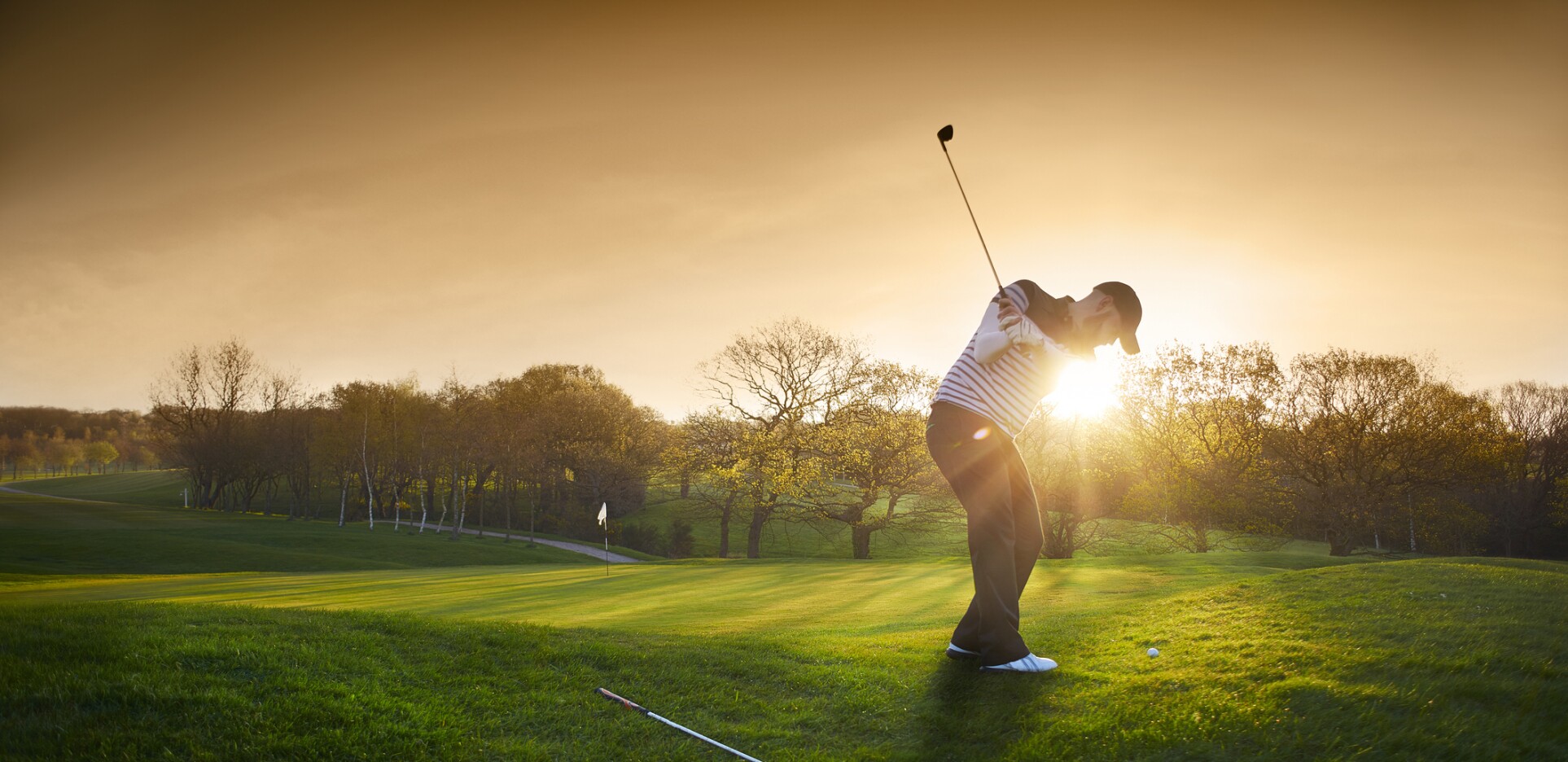Golfer on golf course at sunset 
